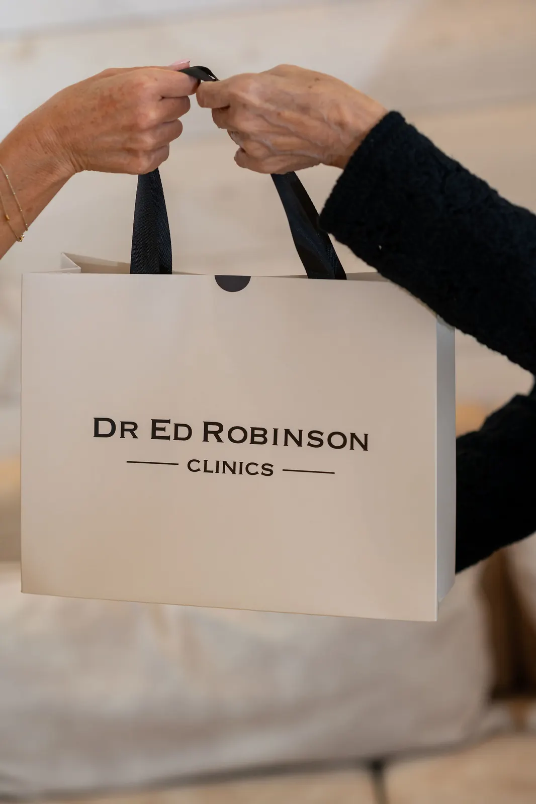 Dr Ed Robinson Clinics branded gift bag being handed to a patient